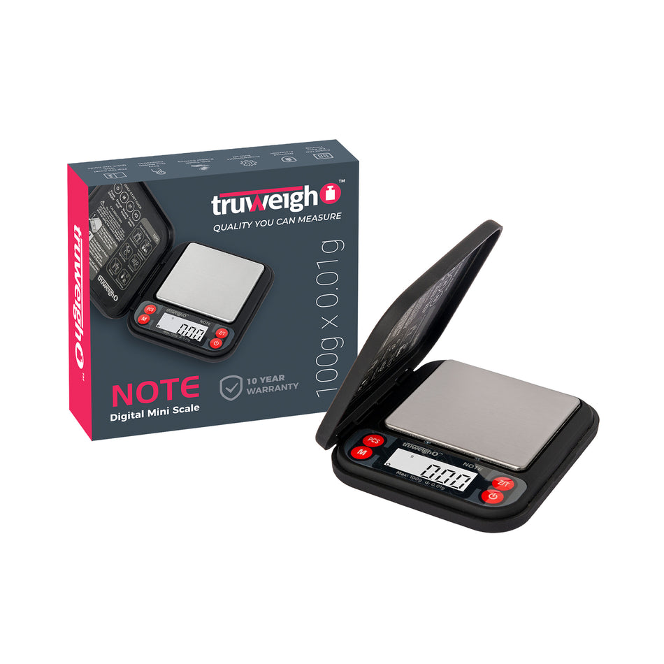 The black Truweigh Note pocket scale is shown open, turned on, and sitting next to the box