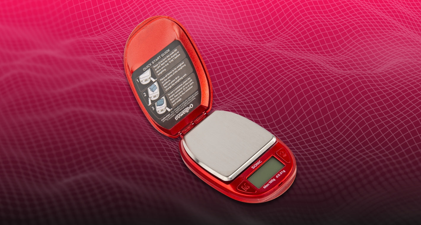 The new design of the Truweigh Sonic compact pocket scale in red. The cover is lifted to reveal the platform and digital screen.